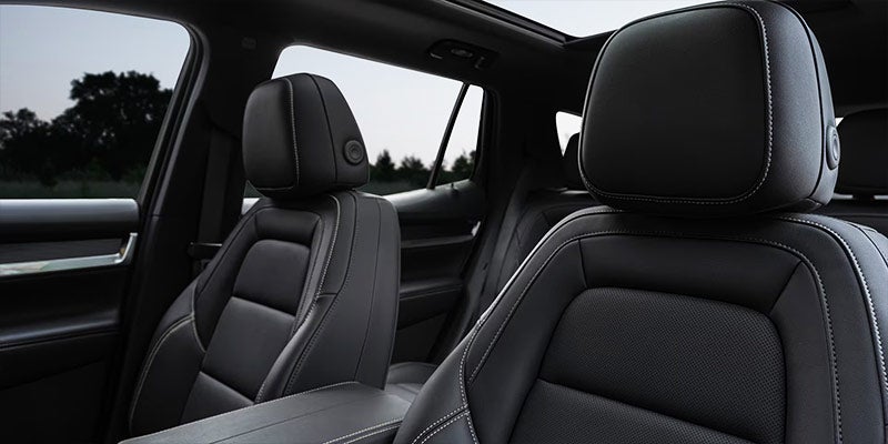 Black leather car seats with white stitching and a sunroof, viewed from the passenger side.