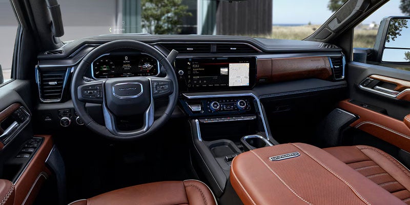 Luxurious car interior with a black dashboard, wood trim, dual digital displays, and rich brown leather seats.