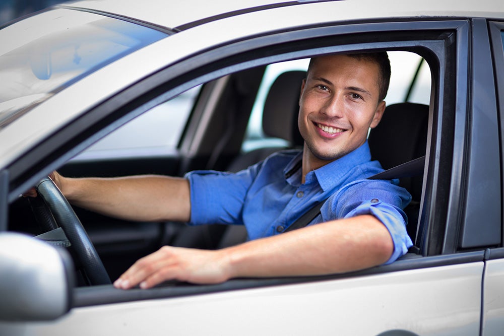 smiling man in blue shirt in the car