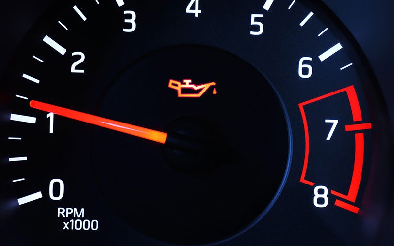 A car's speedometer displays an oil pressure warning light illuminated in yellow.